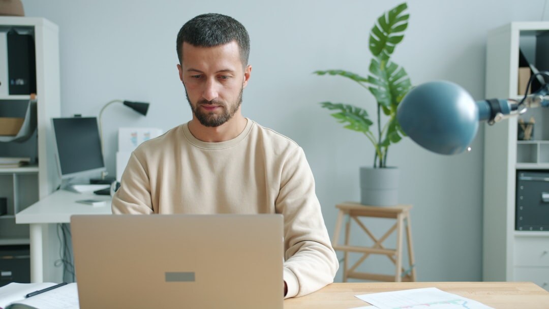 Person working on digital newsletter with laptop in modern workspace